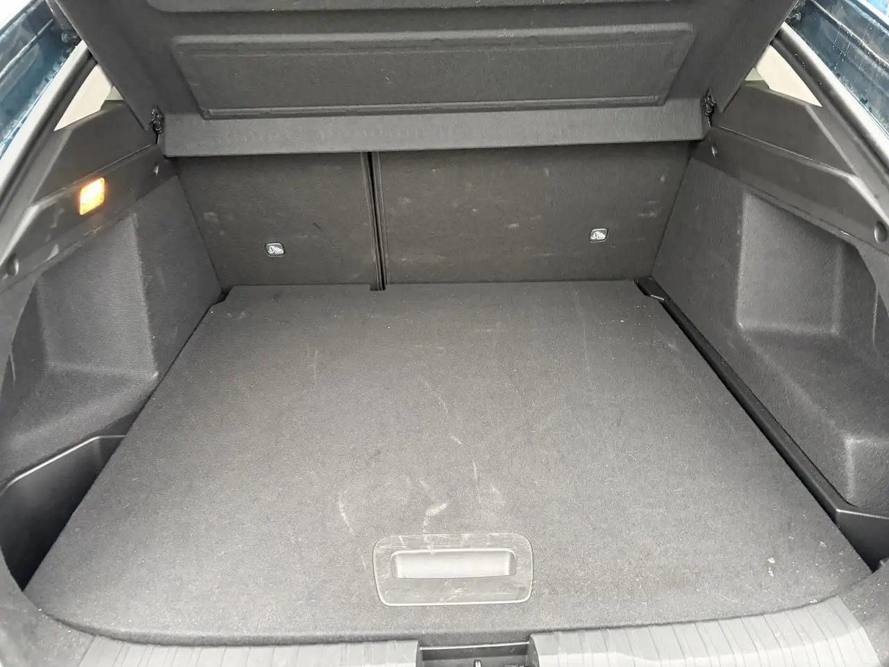 Coffre ouvert vu de l'arrière du Renault Arkana bleu Zanzibar, avec plancher plat et éclairage intérieur.