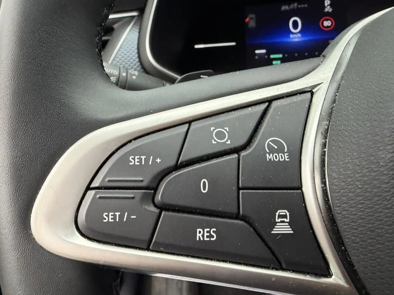 Gros plan sur les commandes au volant gauche du Renault Arkana 2025, finition noire avec contour argenté.