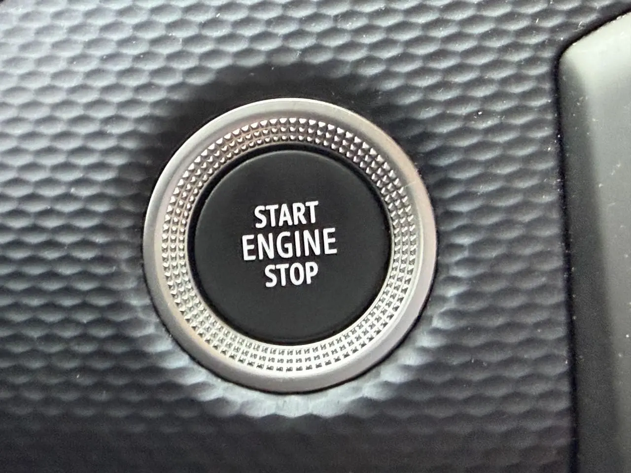 Gros plan sur le bouton Start Engine Stop entouré d’une finition texturée noire dans l’habitacle Renault Arkana Bleu Zanzibar.