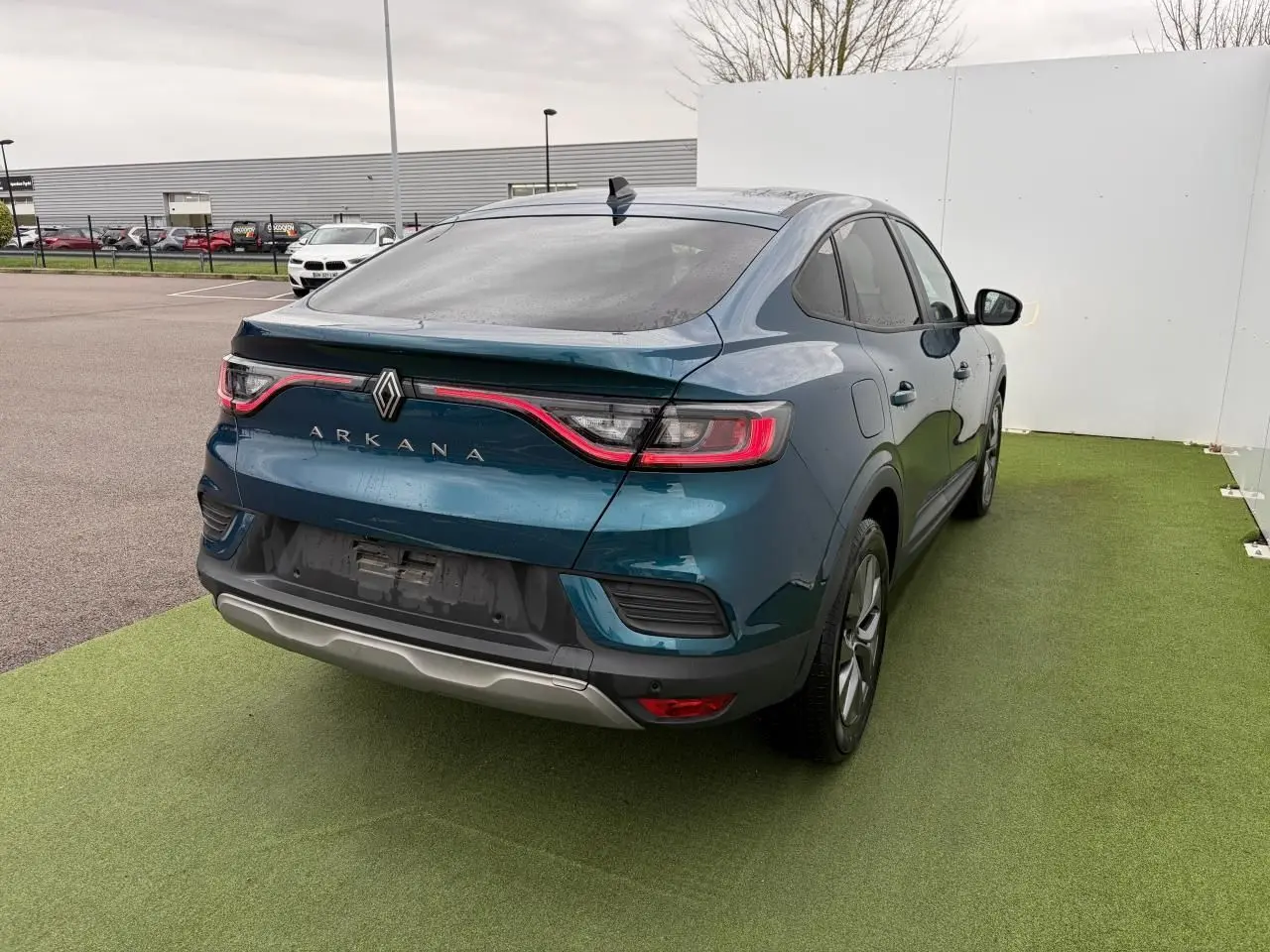 Vue 3/4 arrière droite d'une Renault Arkana bleu Zanzibar métal avec feux arrière LED et vitres surteintées.
