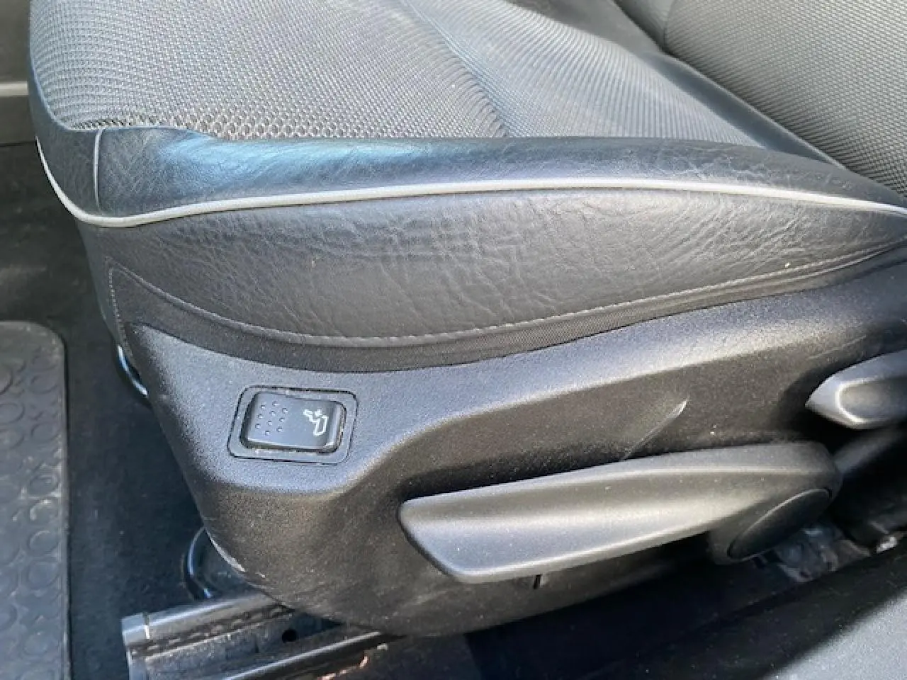 Gros plan sur le côté gauche du siège conducteur en cuir noir du Fiat 500X Cross 2016, avec réglage manuel et bouton de chauffage.