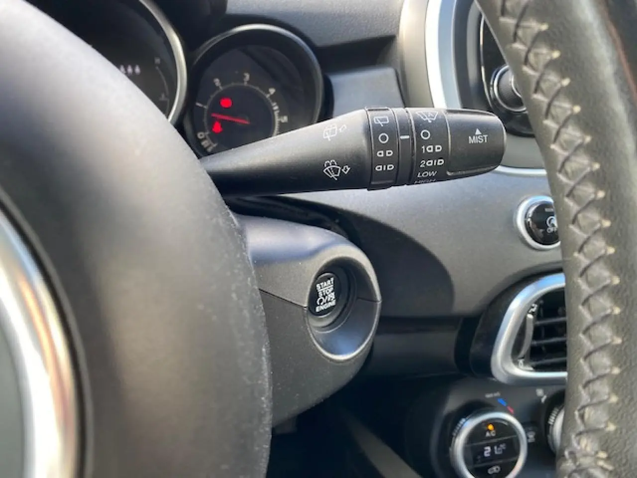 Détail du commodo d’essuie-glace et bouton start/stop sur le tableau de bord noir d’une Fiat 500X Cross 2016.