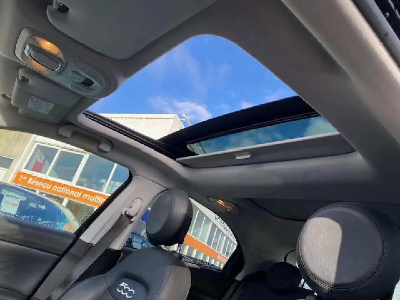 Vue intérieure du toit ouvrant panoramique et des sièges noirs du Fiat 500X Cross diesel 2016.