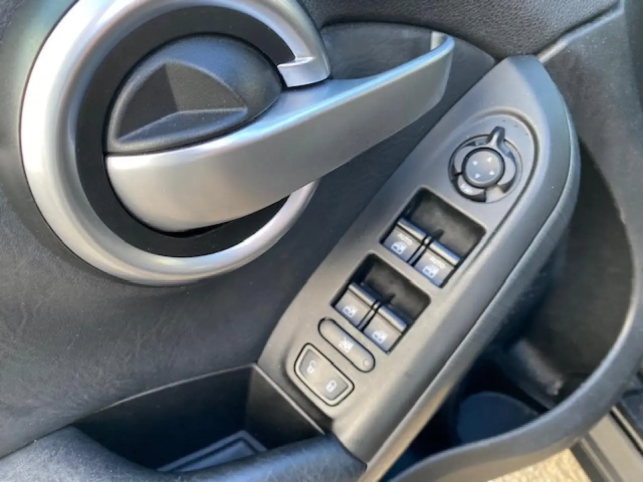 Poignée de porte intérieure et commandes des vitres côté gauche d'un Fiat 500X noir Cross 2016.