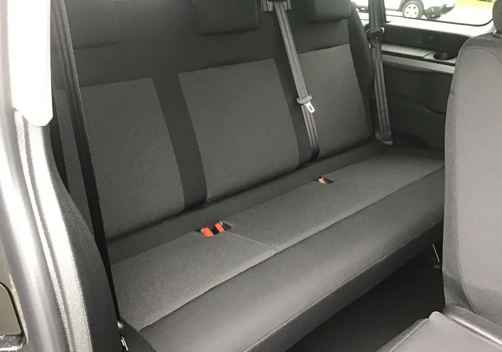 Vue intérieure du siège arrière en tissu gris foncé du FIAT Scudo Combi XL 9 places, avec ceintures de sécurité visibles.