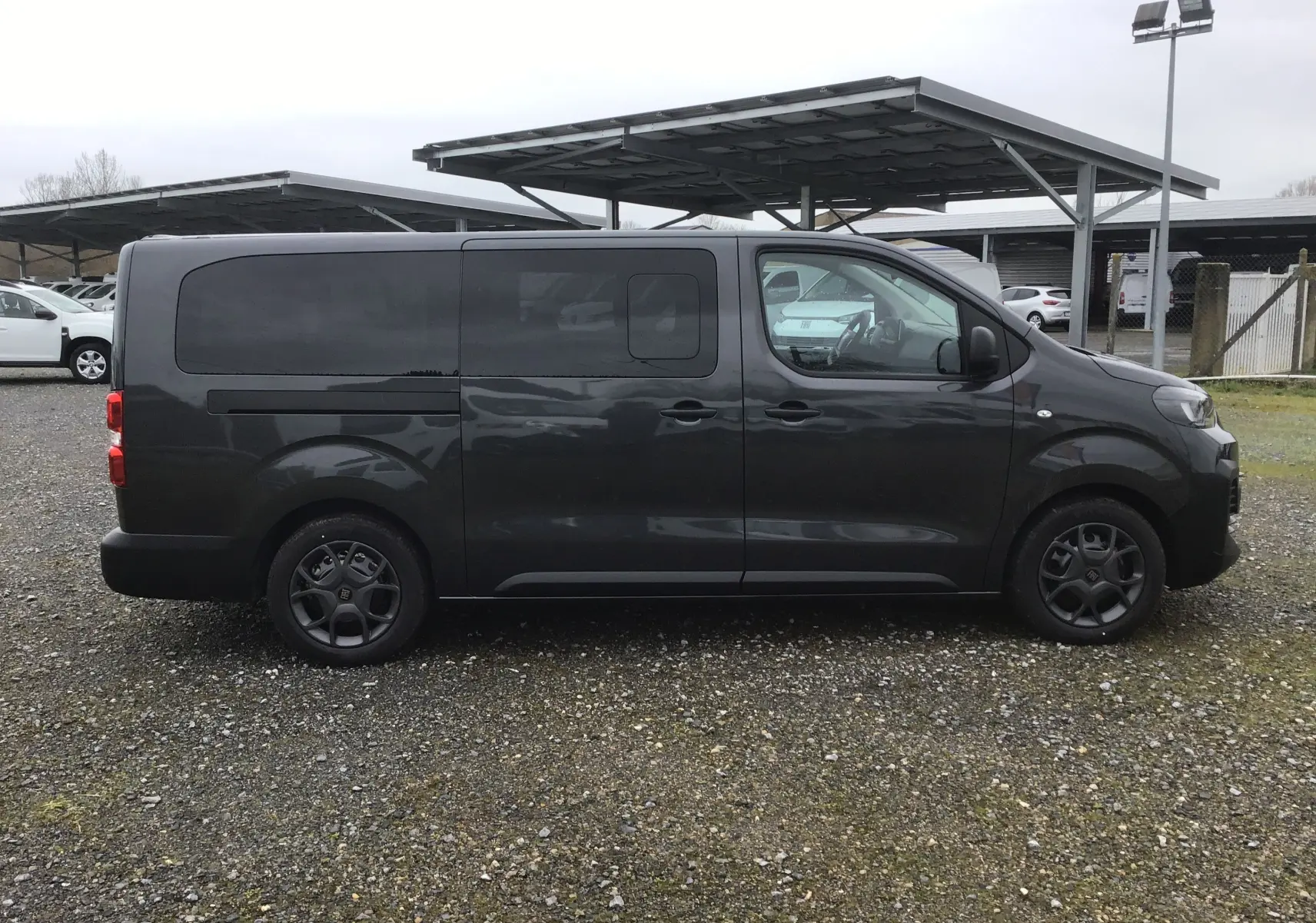 Vue de profil côté droit d’un FIAT Scudo Combi gris titane avec vitres latérales coulissantes surteintées en rang 2.