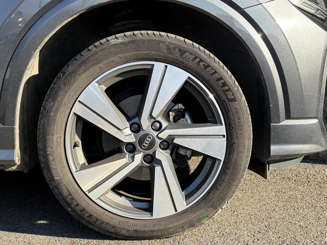 Gros plan sur la roue avant droite avec jante alliage 18 pouces et carrosserie gris Daytona nacré d’un Audi Q2 2024.