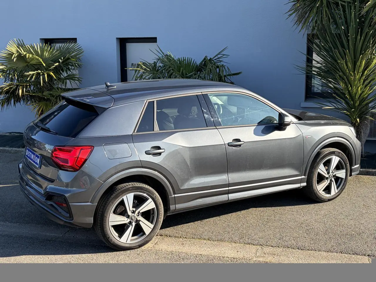 Audi Q2 gris Daytona en vue de profil côté droit, avec jantes alliage 18 pouces et vitres arrière surteintées.