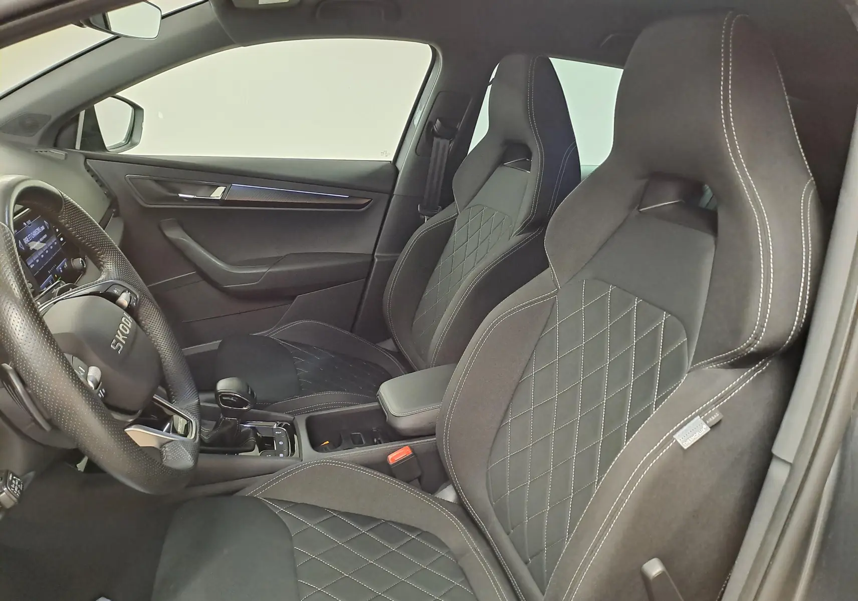 Vue intérieure côté conducteur du Skoda Karoq 2.0 TDI 150 DSG7 Sportline avec sièges noirs et volant multifonction.