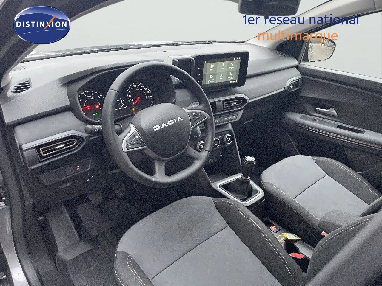 Vue intérieure côté conducteur du Dacia Jogger 2026, tableau de bord et sièges en tissu gris avec volant multifonction.