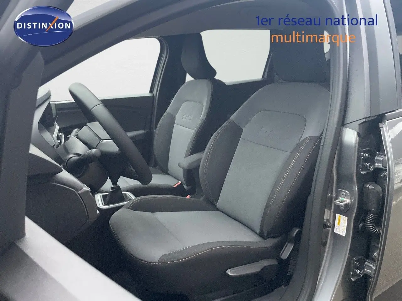 Vue intérieure côté conducteur du Dacia Jogger gris schiste métal, mettant en valeur les sièges tissu gris et noir avec surpiqûres.
