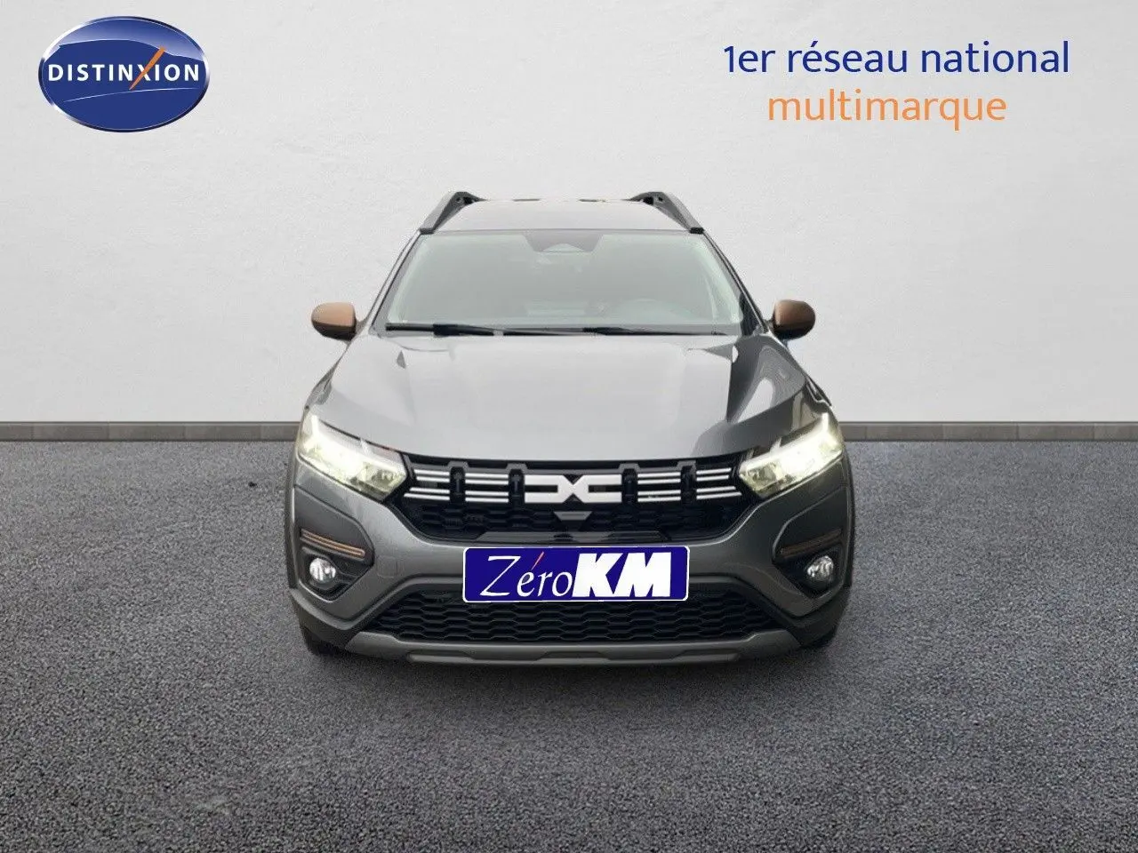 Vue avant du Dacia Jogger gris schiste métal avec calandre noire et phares allumés sur fond neutre.