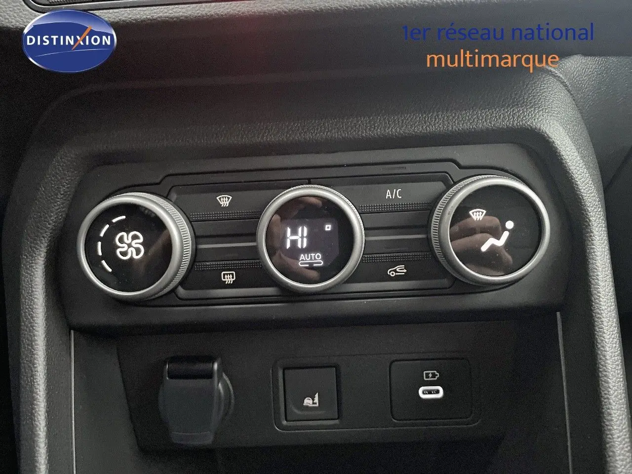 Vue rapprochée du tableau de bord du Dacia Jogger 2026, montrant les commandes de climatisation et prises USB en plastique noir.