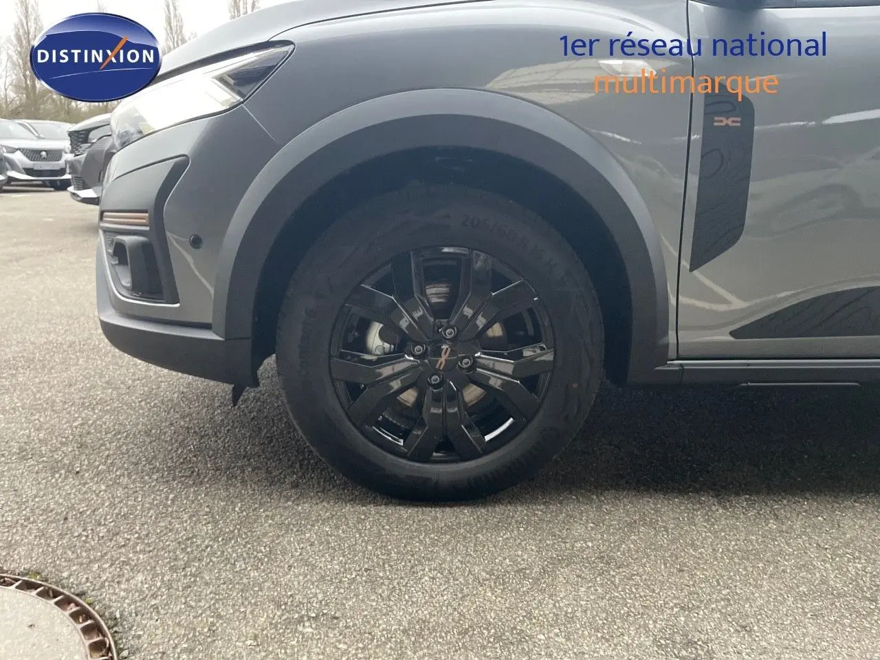 Vue latérale du côté avant gauche du Dacia Jogger gris schiste métal, mettant en valeur la roue noire et l'élément décoratif latéral.