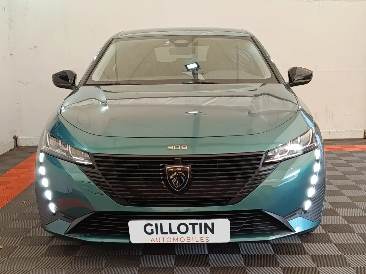 Vue frontale d'une Peugeot 308 2023 vert métallisé avec feux LED verticaux et calandre noire distinctive.