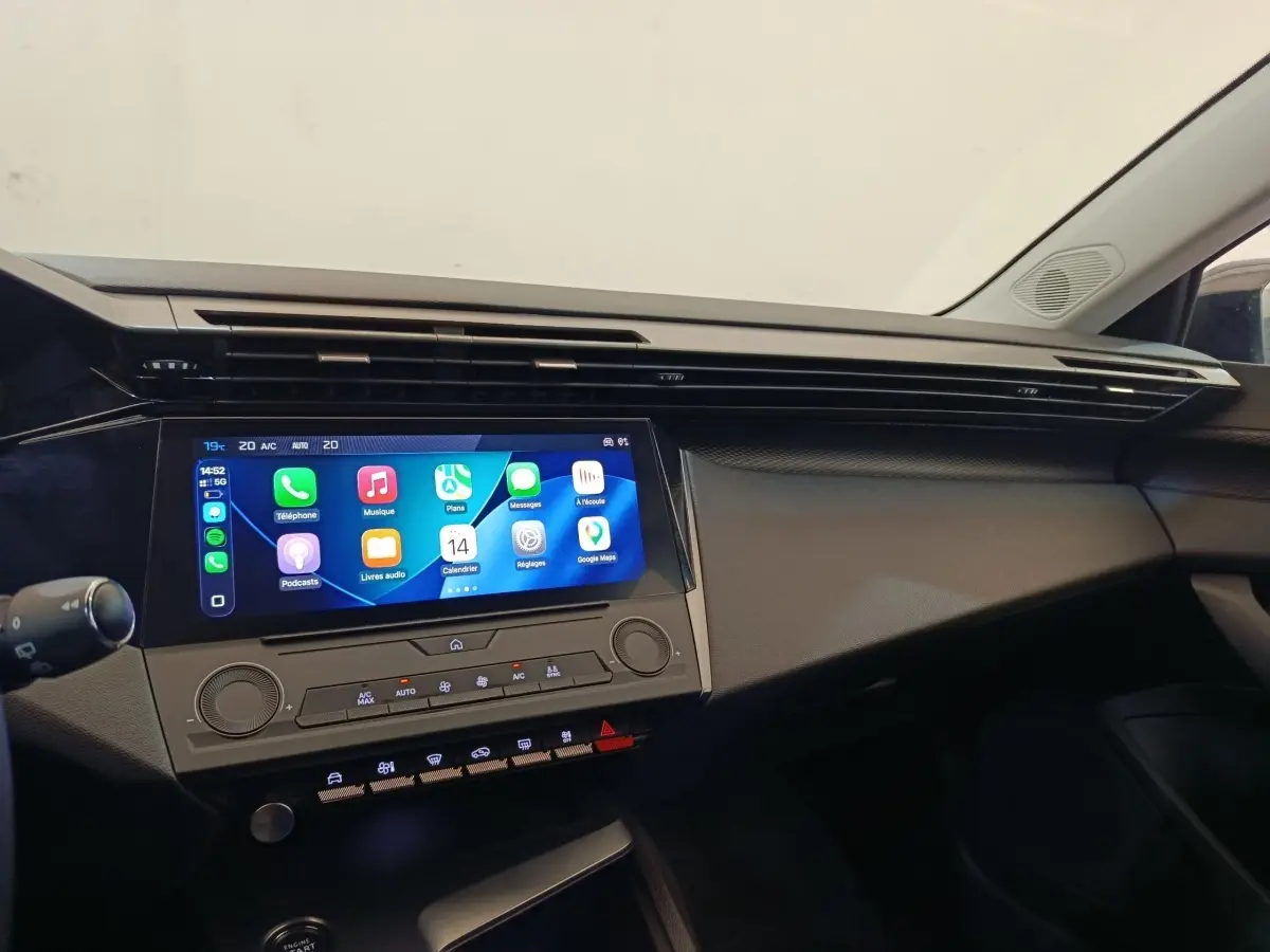 Tableau de bord intérieur de Peugeot 308 2023, vue de face, écran tactile central allumé avec interface Apple CarPlay.