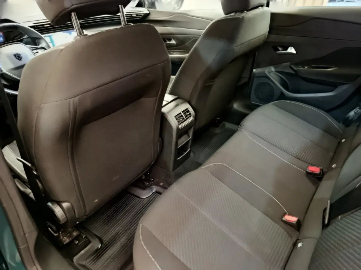Vue intérieure arrière droite du Peugeot 308 2023 avec sièges tissu noirs et console centrale avec aérateurs.