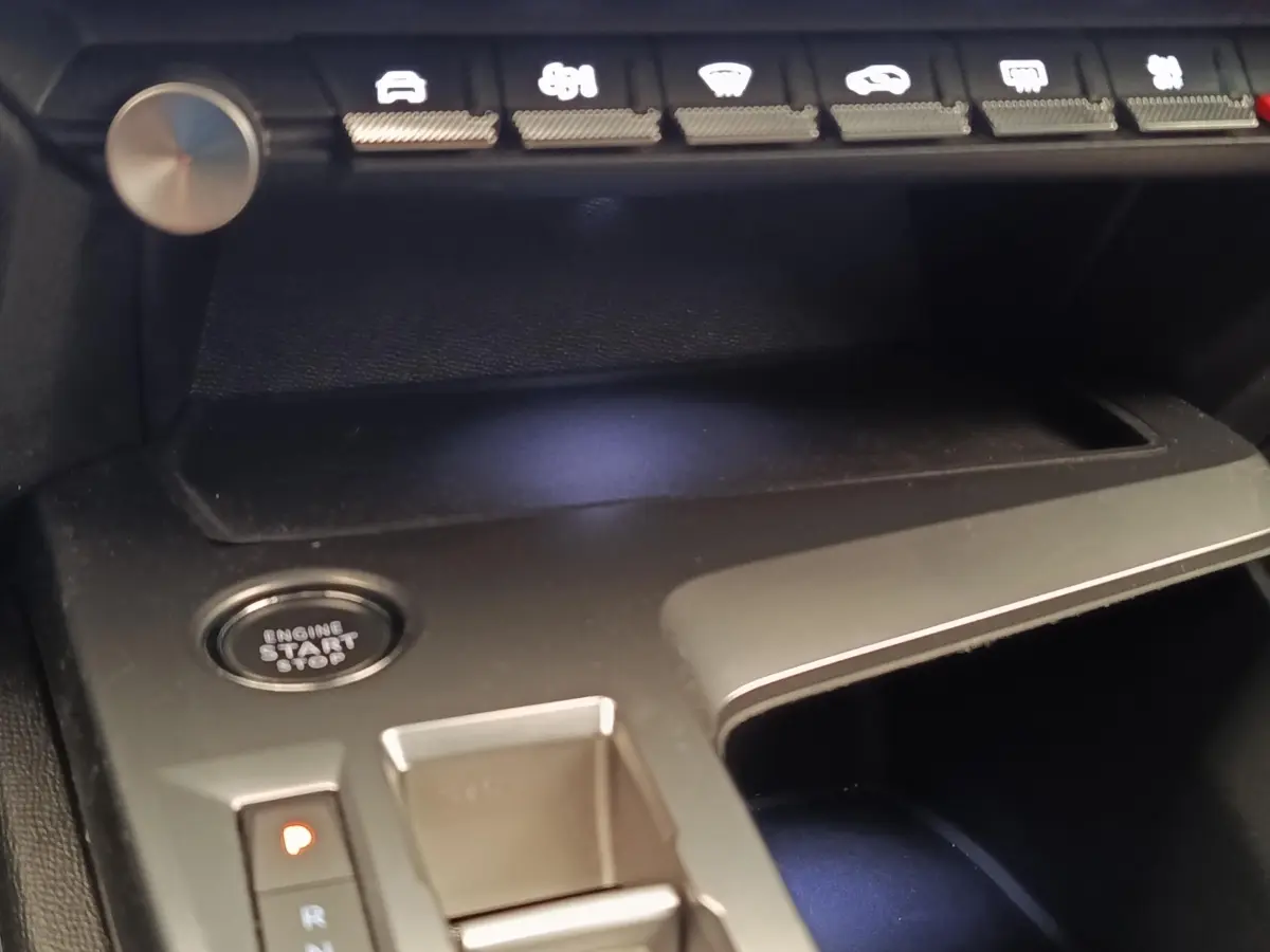 Détail intérieur de la console centrale noire de la Peugeot 308 2023 avec bouton démarrage et commandes tactiles.