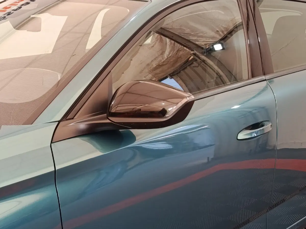 Vue rapprochée du côté gauche de la Peugeot 308 2023 en teinte bleue avec rétroviseur noir brillant et poignée chromée.