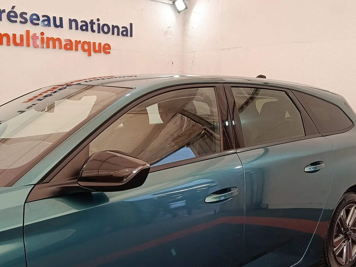 Vue latérale gauche d'une Peugeot 308 2023 vert métallisé avec rétroviseur noir et poignées de porte intégrées.