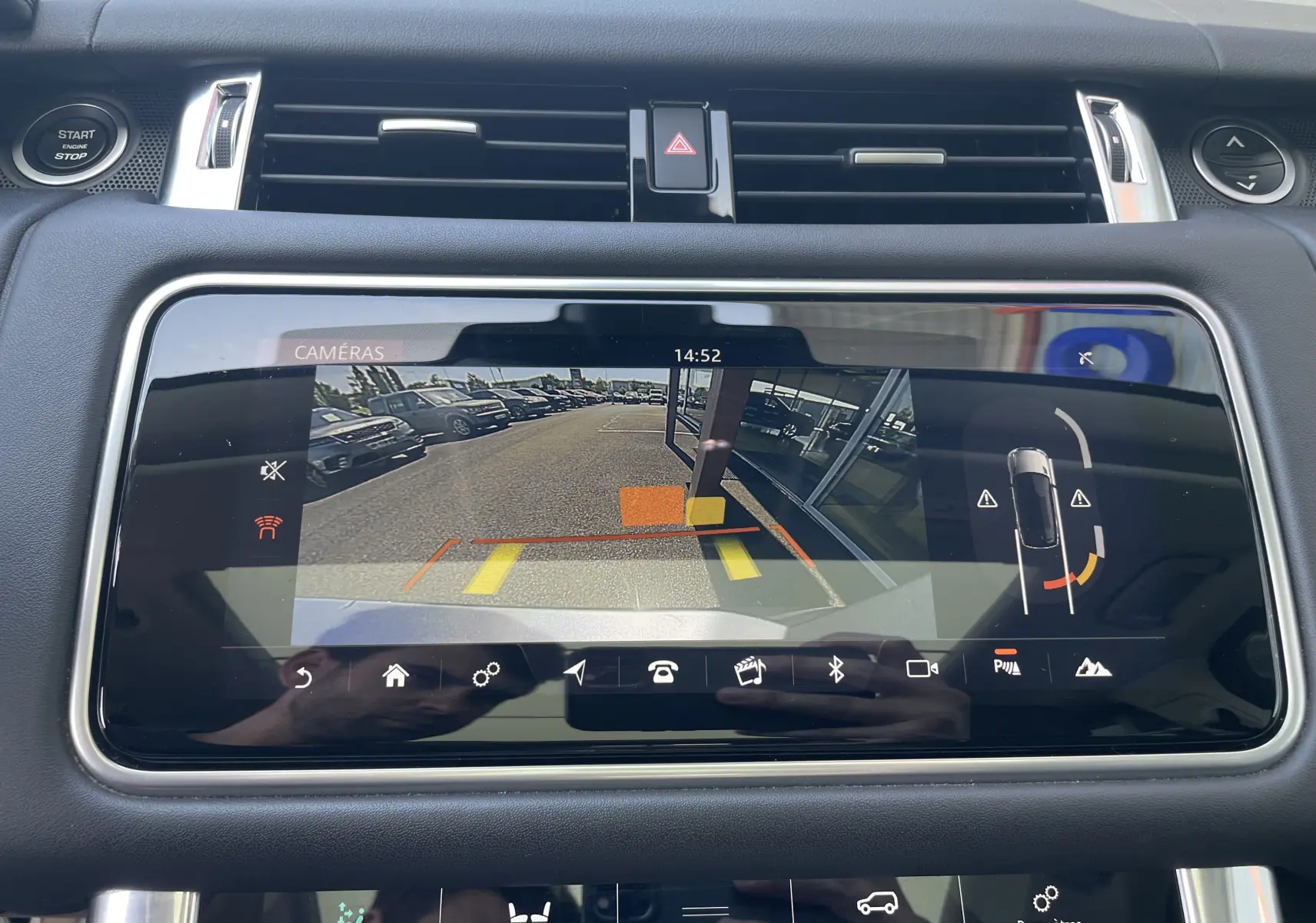 Écran tactile intérieur du Range Rover Sport gris montrant la caméra de recul et l’aide au stationnement.