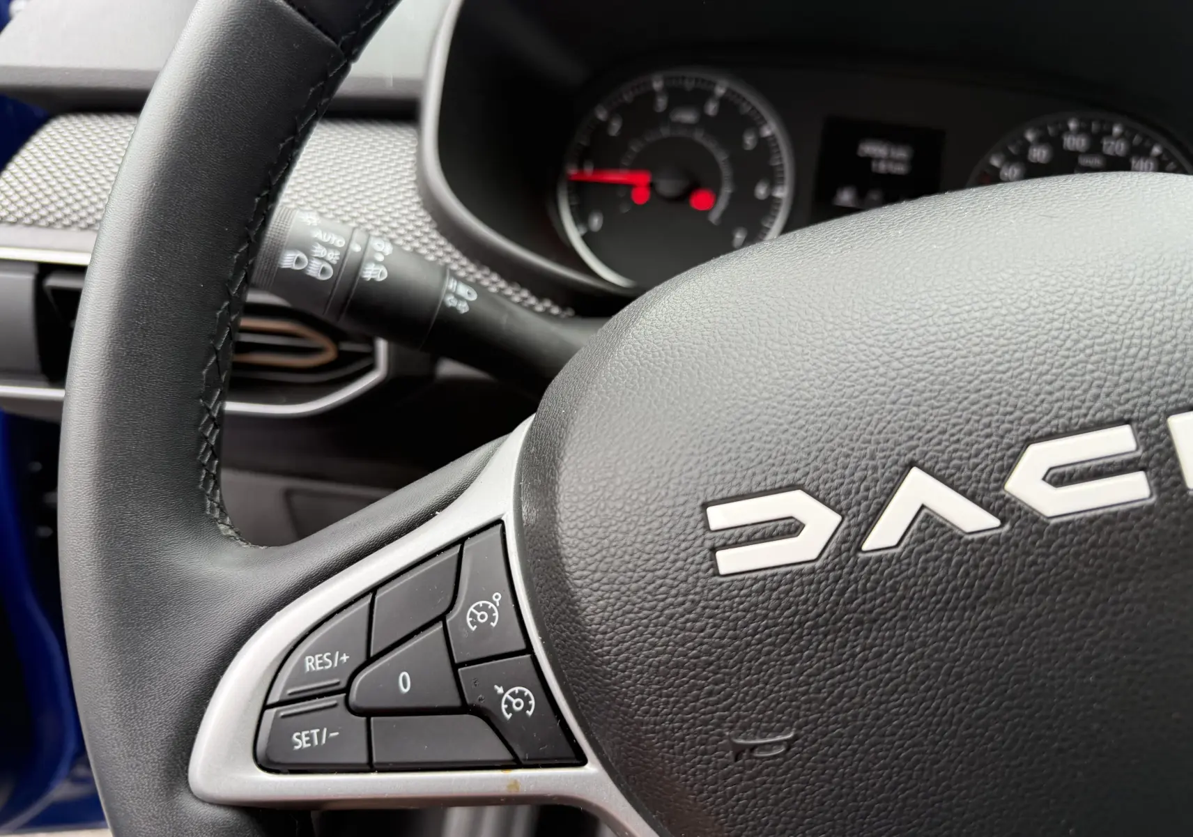 Gros plan sur le volant noir de la Dacia Sandero Stepway 2025, montrant les commandes de régulateur de vitesse côté gauche.