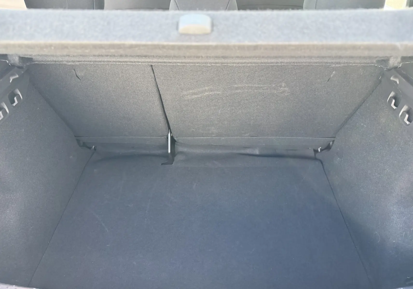 Vue intérieure du coffre spacieux et vide de la Dacia Sandero Stepway TCE 90 Gris Schiste Métal, banquette arrière rabattue partiellement.