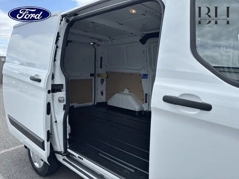 Vue côté droit du Ford Transit Custom blanc glacier 2023 avec porte latérale ouverte montrant l'intérieur utilitaire vide.