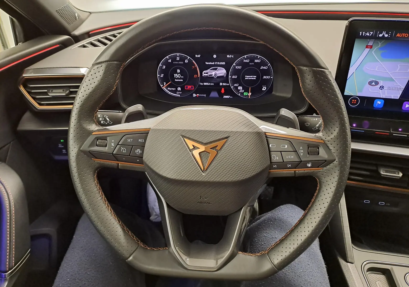 Vue rapprochée du volant perforé avec logo CUPRA cuivré et tableau de bord numérique du Leon 1.5 eTSI gris magnétique 2023.