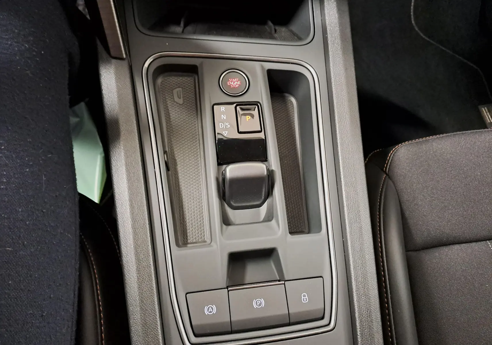 Vue plongeante sur la console centrale grise de la CUPRA Leon 1.5 eTSI 2023 avec levier de boîte auto et bouton start/stop.
