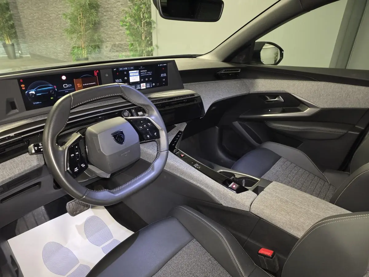 Vue intérieure avant droite du Peugeot 3008 gris, avec tableau de bord numérique et volant compact cuir noir.