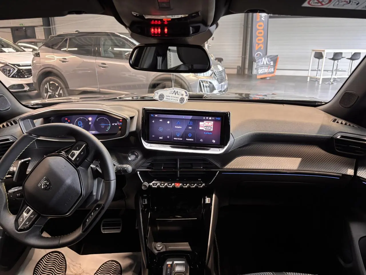 Vue intérieure avant du Peugeot 2008 blanc 2025, tableau de bord moderne avec écran tactile et volant compact cuir.