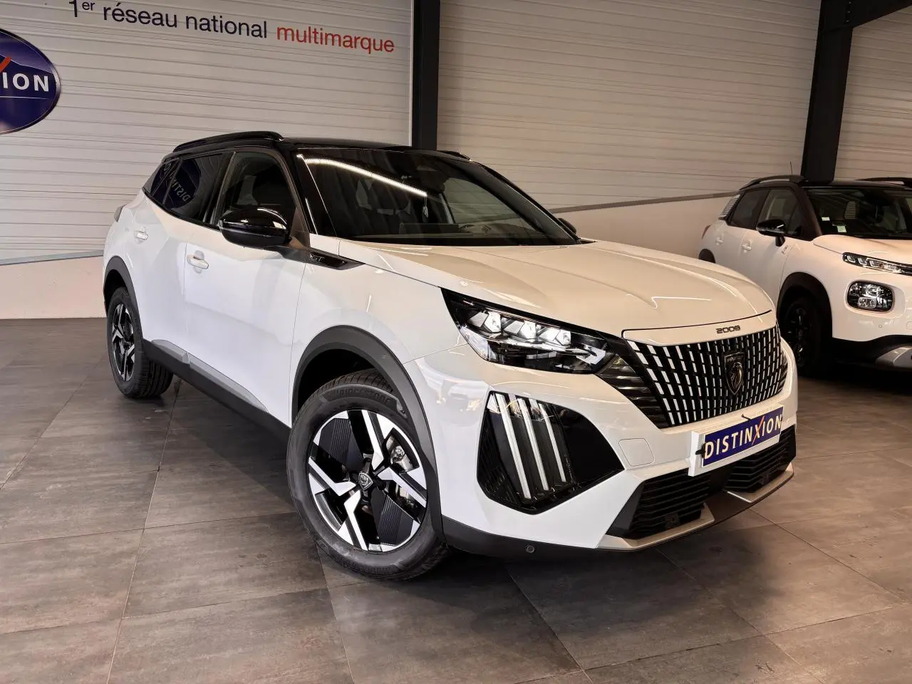 Peugeot 2008 blanc vue 3/4 avant droit avec toit noir, calandre noire et jantes alliage bi-ton.