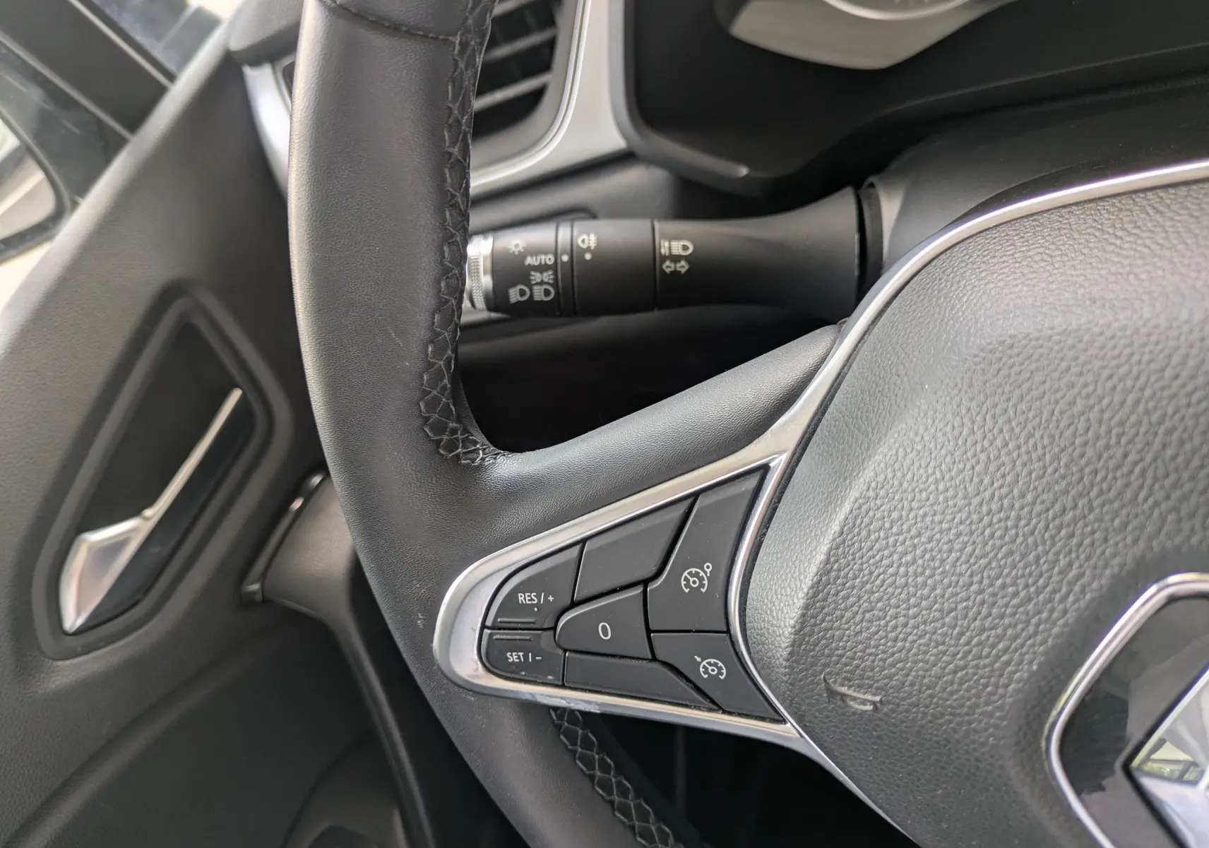 Gros plan sur le volant noir du Renault Captur Business DCI 95 2020, montrant les commandes de régulateur de vitesse côté gauche.