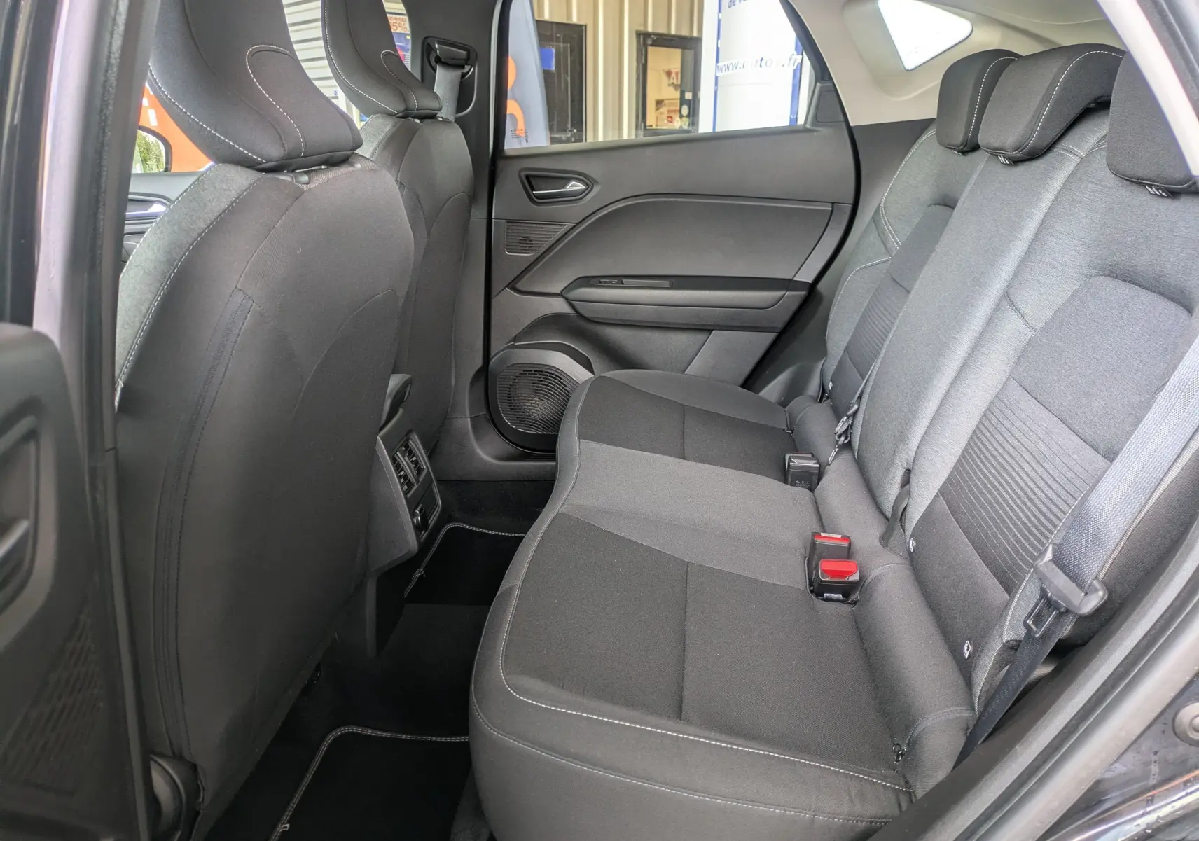 Vue intérieure côté droit des sièges arrière noirs du Renault Captur Business DCI 95 de 2020 avec ceintures et appuie-têtes.