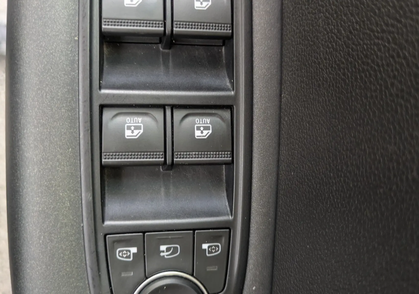 Vue rapprochée des commandes de lève-vitres et réglages des rétroviseurs côté conducteur d’un Renault Captur noir 2020.