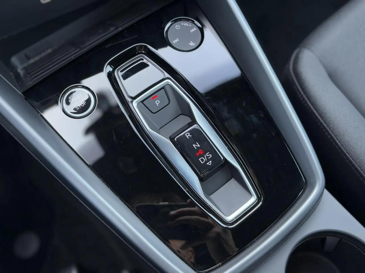 Vue rapprochée de la console centrale noire brillante avec levier de vitesses automatique et bouton start/stop de l'Audi A3 Sportback 2024.