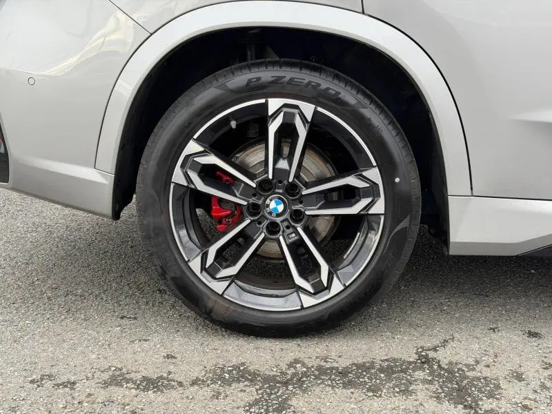 Gros plan sur la roue arrière droite d'une BMW X1 Spacesilber métal avec jante alu noire et grise et étrier de frein rouge.