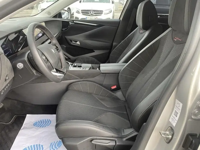 Vue intérieure côté conducteur du DS4 gris 2023, sièges Performance Line en tissu et cuir avec surpiqûres rouges.