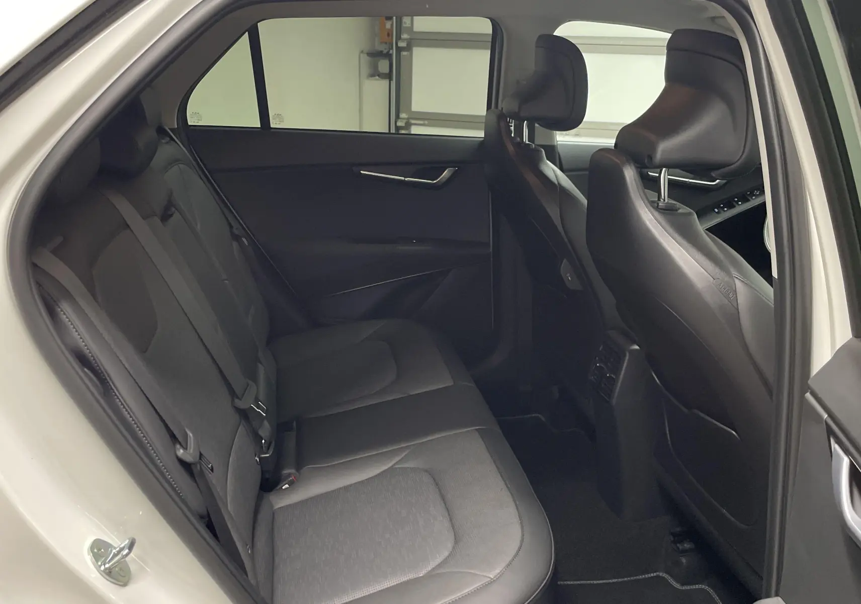 Vue intérieure côté gauche des sièges arrière en tissu gris du Kia Niro blanc 2025 version hybride Premium.