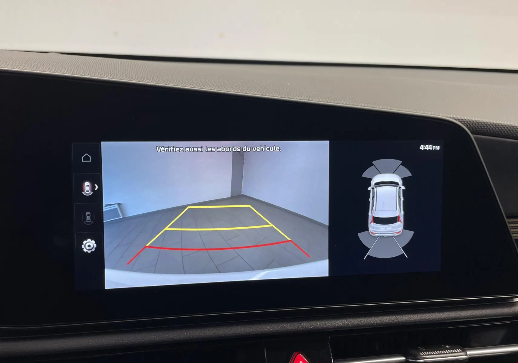 Écran de caméra de recul du Kia Niro blanc 2025 montrant l’arrière avec lignes de guidage colorées et vue 360° du véhicule.