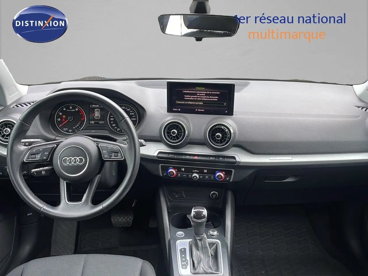 Vue intérieure avant de l'Audi Q2 noir mito metal 2023, tableau de bord moderne avec écran central et volant multifonction.