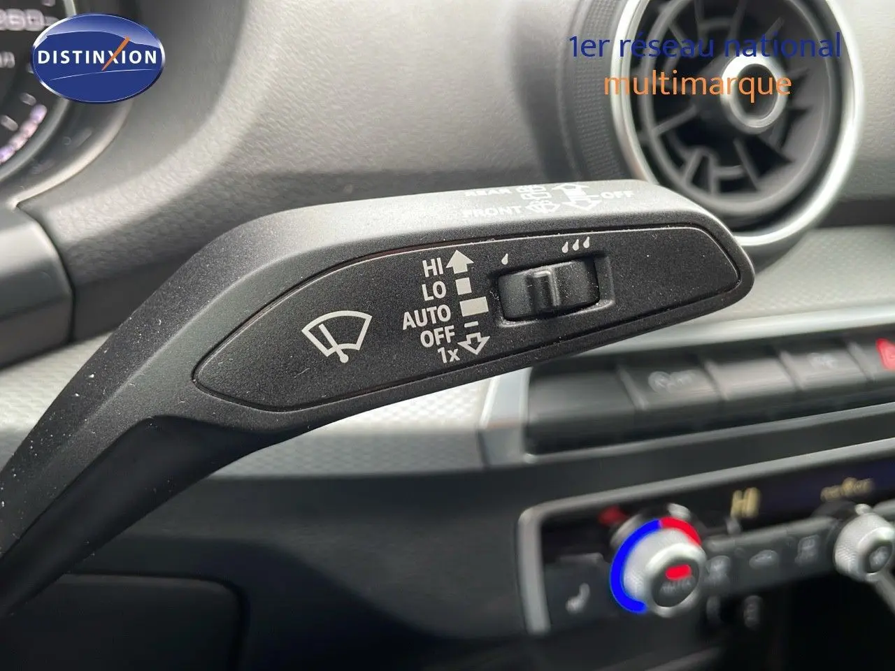 Le levier de commande des essuie-glaces dans l'habitacle de l'Audi Q2 2023 noir mito metal, avec la ventilation en arrière-plan.