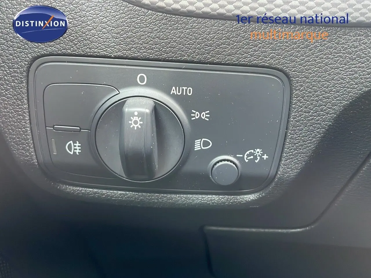 Gros plan sur le sélecteur de phares de l'Audi Q2 35 TFSI S-Line 2023, avec commandes d'éclairage et réglage automatique.