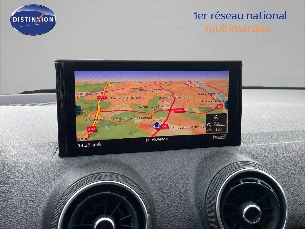Écran GPS en plan rapproché sur le tableau de bord de l'Audi Q2 noir mito metal, avec aérateurs ronds visibles.