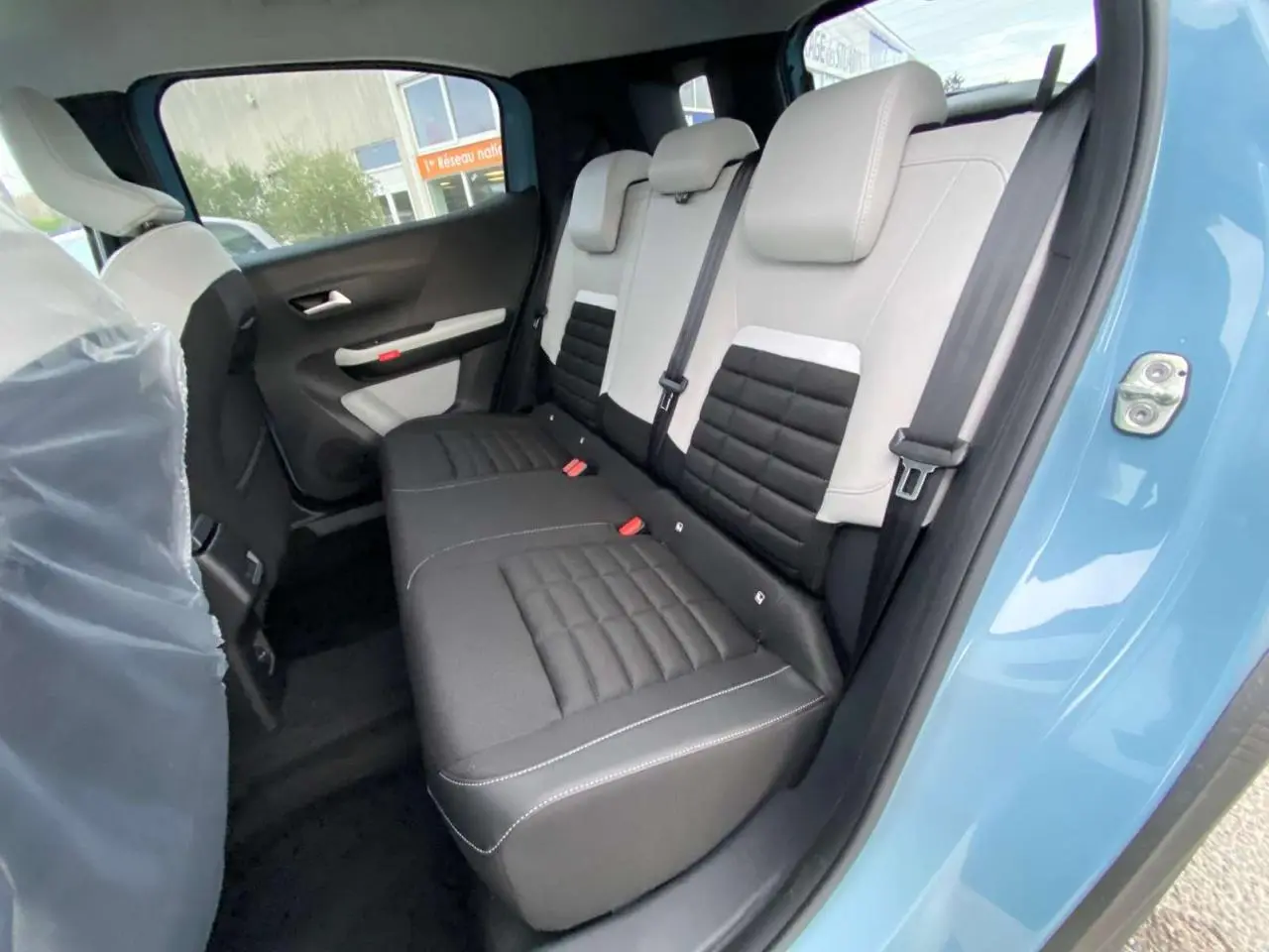 Vue intérieure côté droit sur la banquette arrière bicolore noire et gris clair du Citroën C3 Aircross Bleu Monte Carlo.