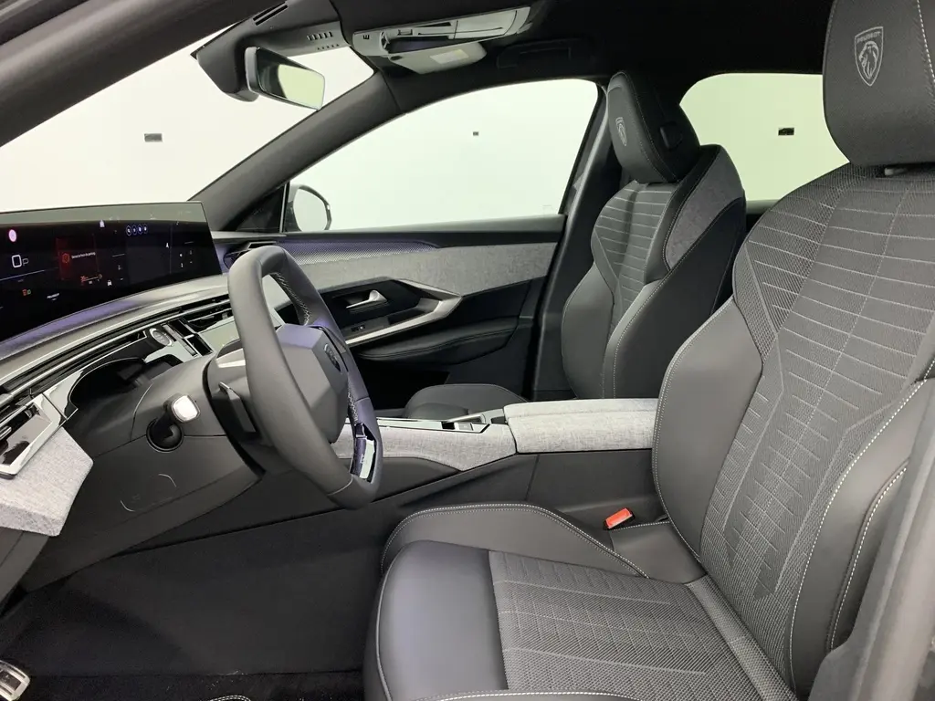Vue intérieure côté conducteur du Peugeot 3008 Hybrid 145 GT avec sellerie tissu gris et volant compact cuir noir.