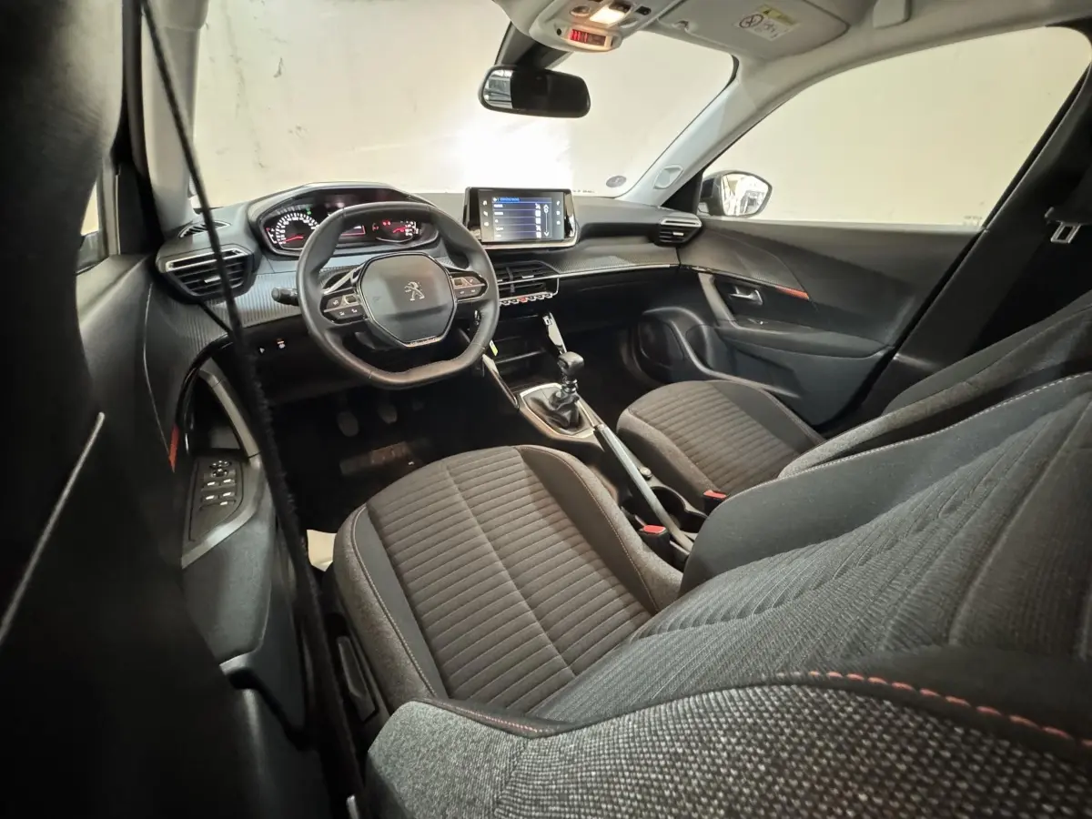 Intérieur avant du Peugeot 2008 noir, vue côté conducteur montrant tableau de bord, volant cuir et console centrale avec boîte manuelle.
