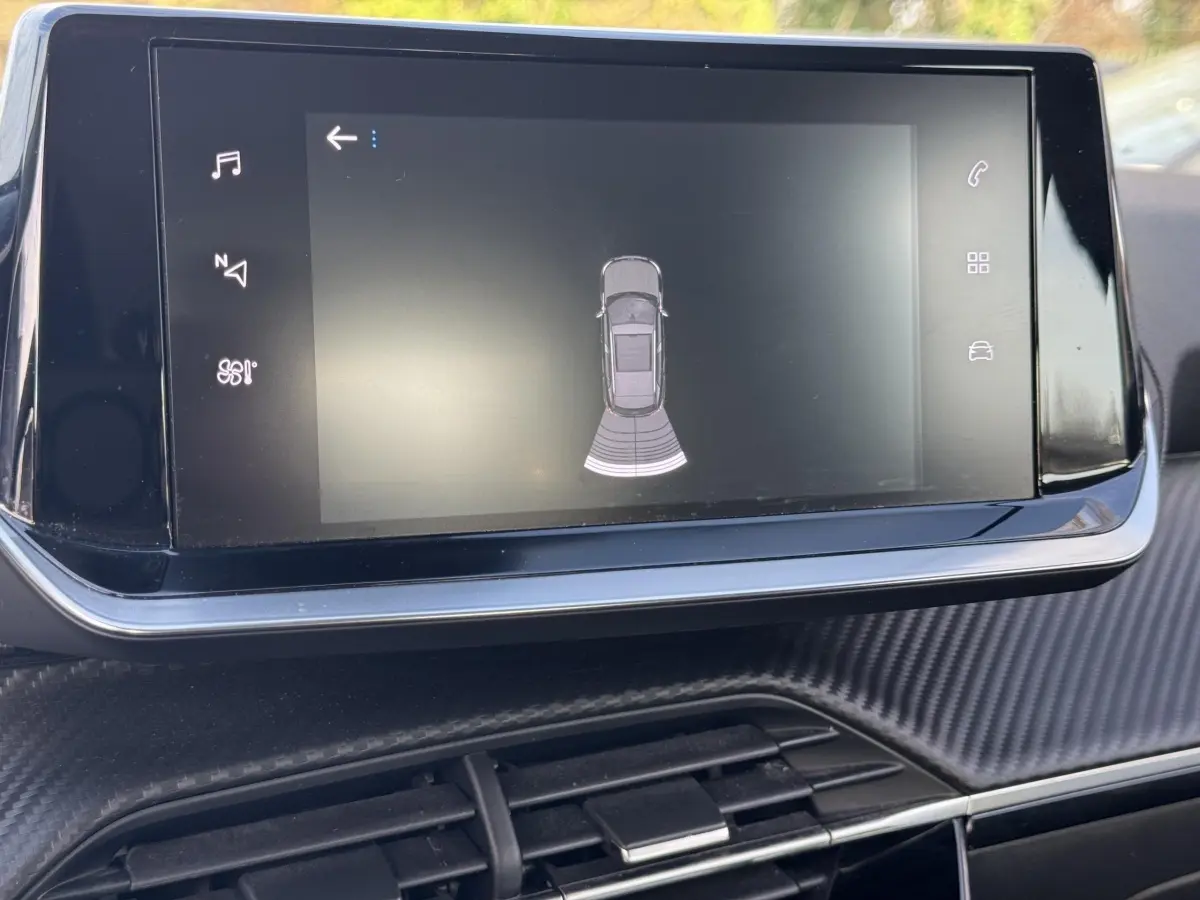 Écran tactile central du tableau de bord de la Peugeot 2008 noir, affichant l'aide au stationnement arrière.