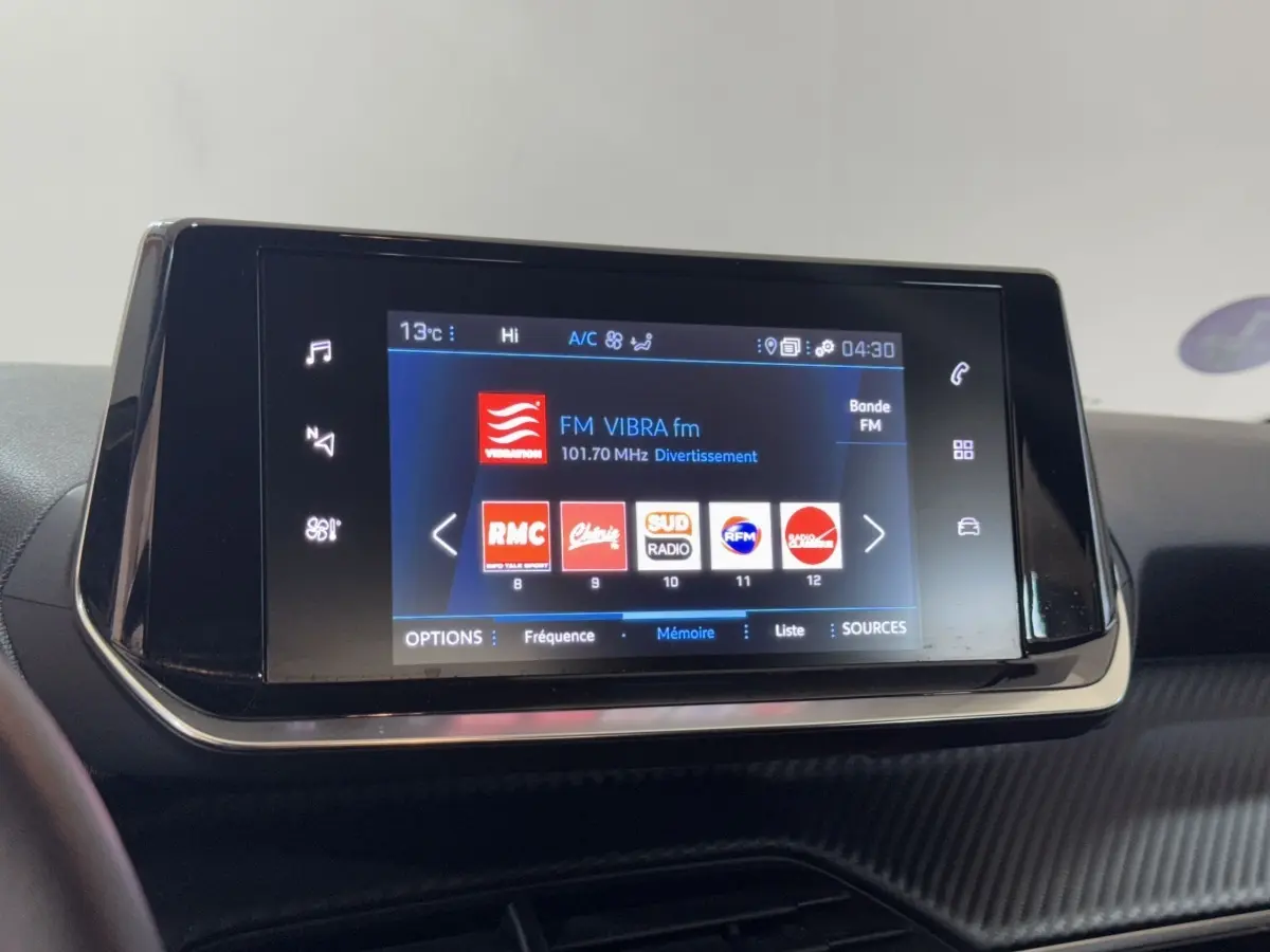 Écran tactile central de la Peugeot 2008 PureTech 130 noir affichant les stations radio FM en intérieur.